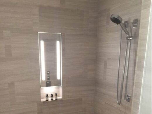 Inside a shower with a detachable shower nozzle and small alcove for shampoo